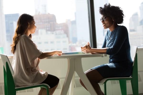 Two women sitting across from each other at a table having a sales conversation bolstered by the BANT model.